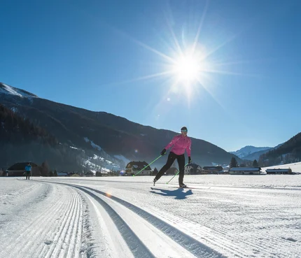 Langläufer bei sonnigem Wetter in verschneiter Berglandschaft