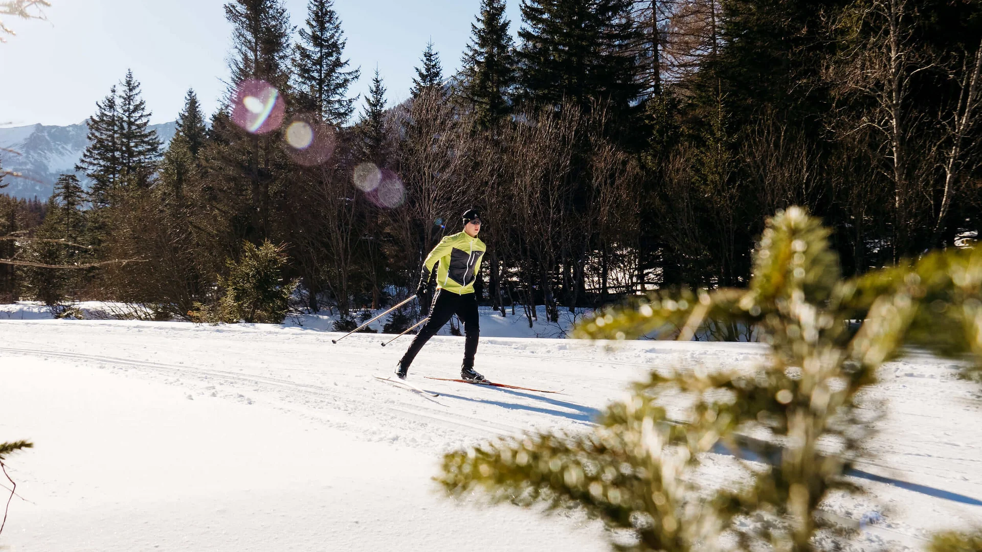 Person beim Langlaufen auf verschneiter Landschaft mit Bäumen im Hintergrund