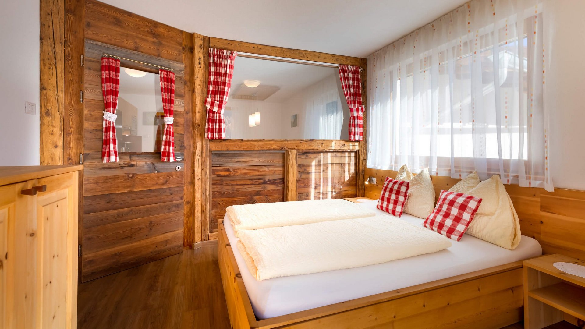 Gemütliches Schlafzimmer mit Holzmöbeln und rotkarierten Vorhängen