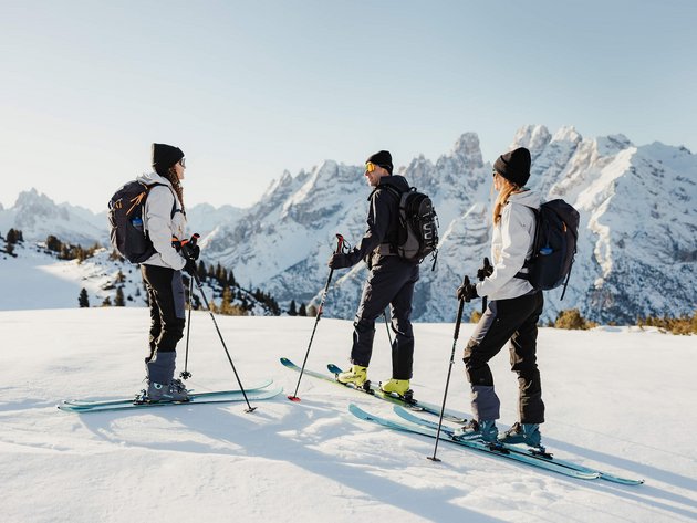 Drei Skifahrer stehen im Schnee vor einer Berglandschaft