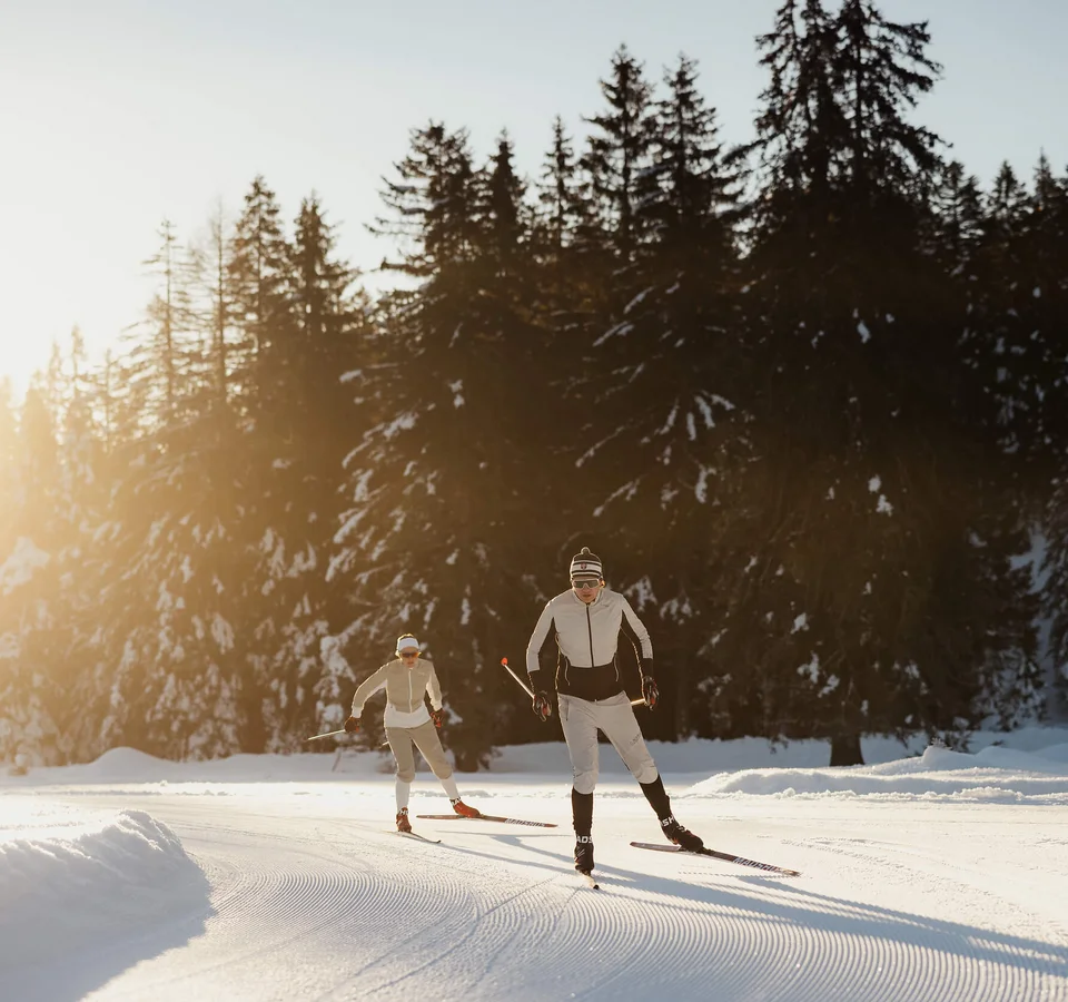 Bergwelten Nordic Experience © Alex Moling Zwei Skifahrer beim Langlauf auf verschneiter Strecke mit Wald im Hintergrund