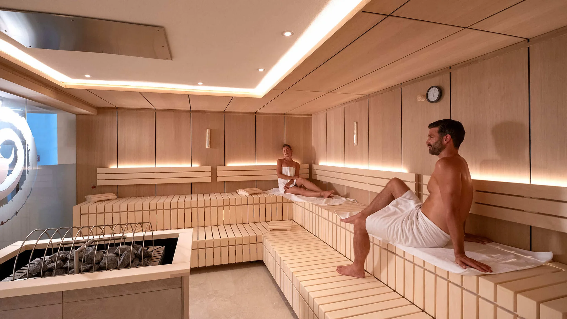Alpenhotel Karwendel **** © Hotel Karwendel Bernhard Rödlach BetriebsGmbH Zwei Personen entspannen in einer modernen Sauna mit Holzverkleidung