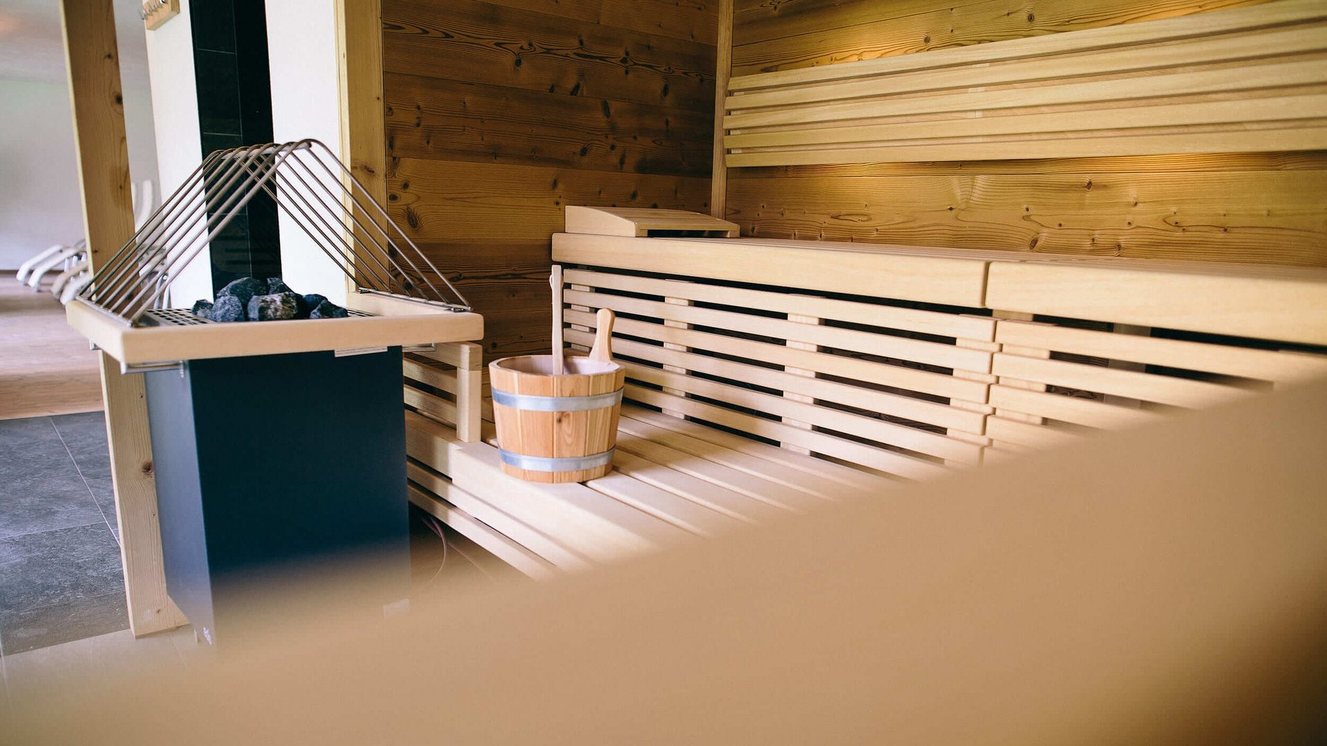 Innenraum einer Sauna mit Holzbänken und Saunaeimer