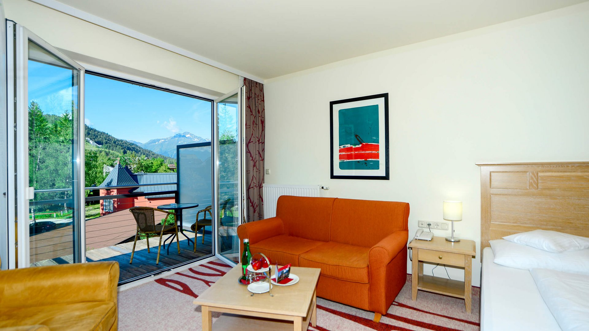 Room with balcony and mountain view, orange sofa and armchair