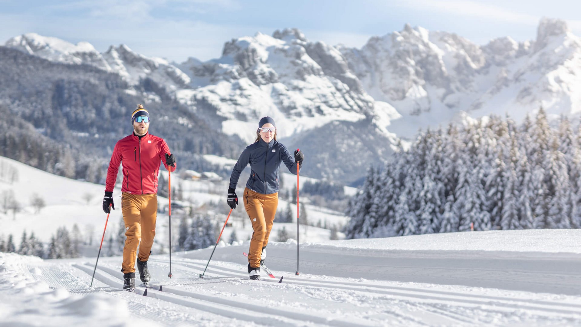Zwei Langläufer im Schnee mit Bergen im Hintergrund
