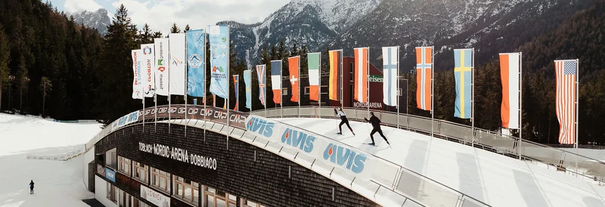 Skilangläufer in der Nordic Arena Dobbiaco vor schneebedeckten Bergen