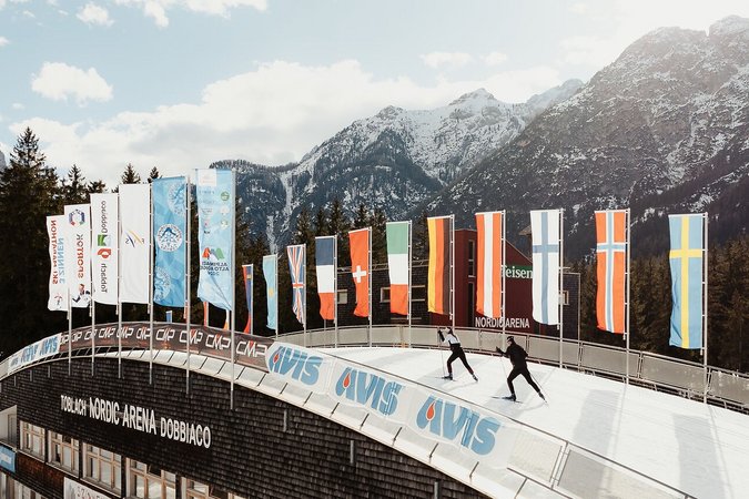 Langlauf Urlaub © Alex Moling Skilangläufer in der Nordic Arena Dobbiaco vor schneebedeckten Bergen