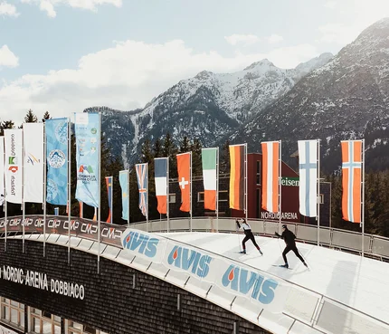 Skilangläufer in der Nordic Arena Dobbiaco vor schneebedeckten Bergen