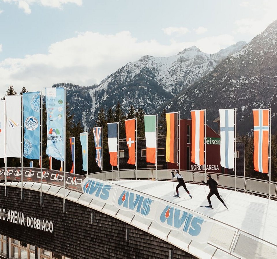 Skilangläufer in der Nordic Arena Dobbiaco vor schneebedeckten Bergen