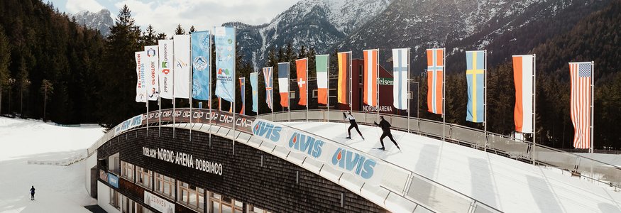 Skilangläufer in der Nordic Arena Dobbiaco vor schneebedeckten Bergen