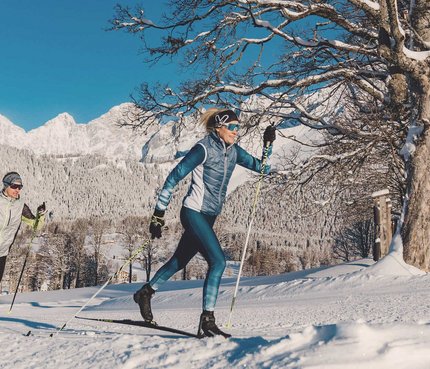 7 Dinge, die du über Schladming-Dachstein wissen musst © TVB Schladming Dachstein - Christine Höflehner Zwei Personen beim Langlaufen vor verschneiten Bergen und klarem Himmel
