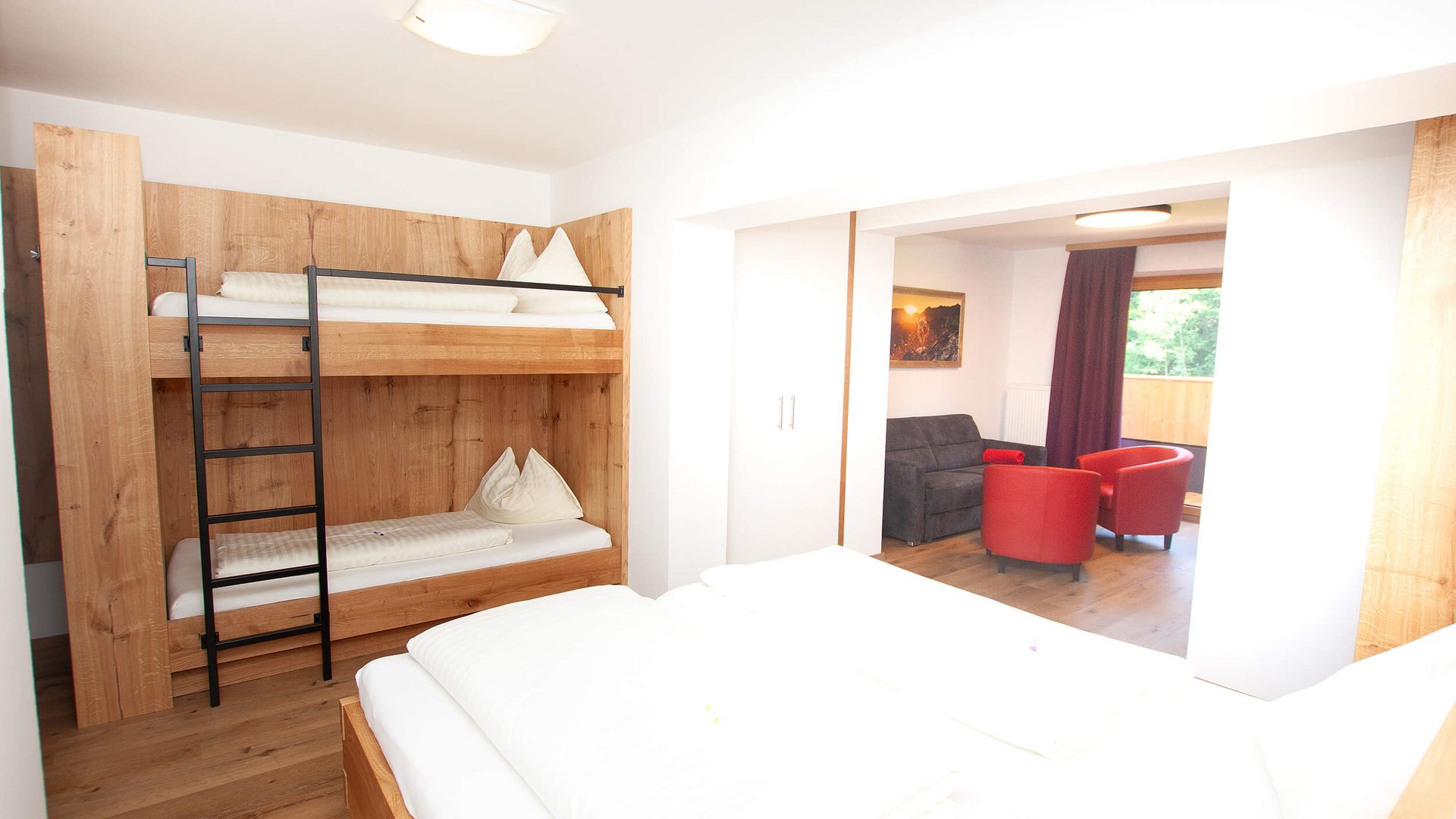 helle Suite mit Etagenbett, Doppelbett und Sitzecke mit rotem Sessel