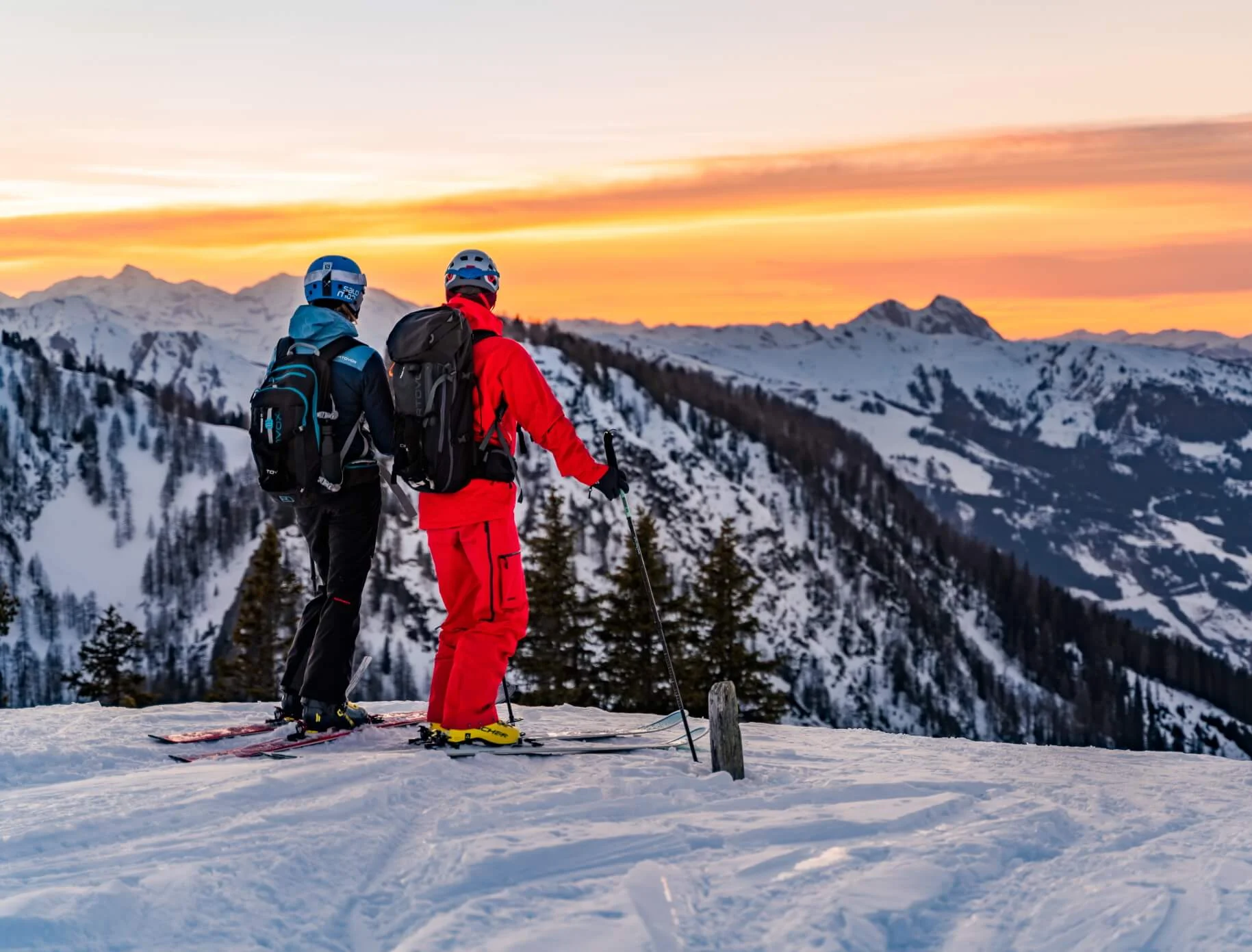 Zwei Skifahrer betrachten Sonnenuntergang in verschneiten Bergen