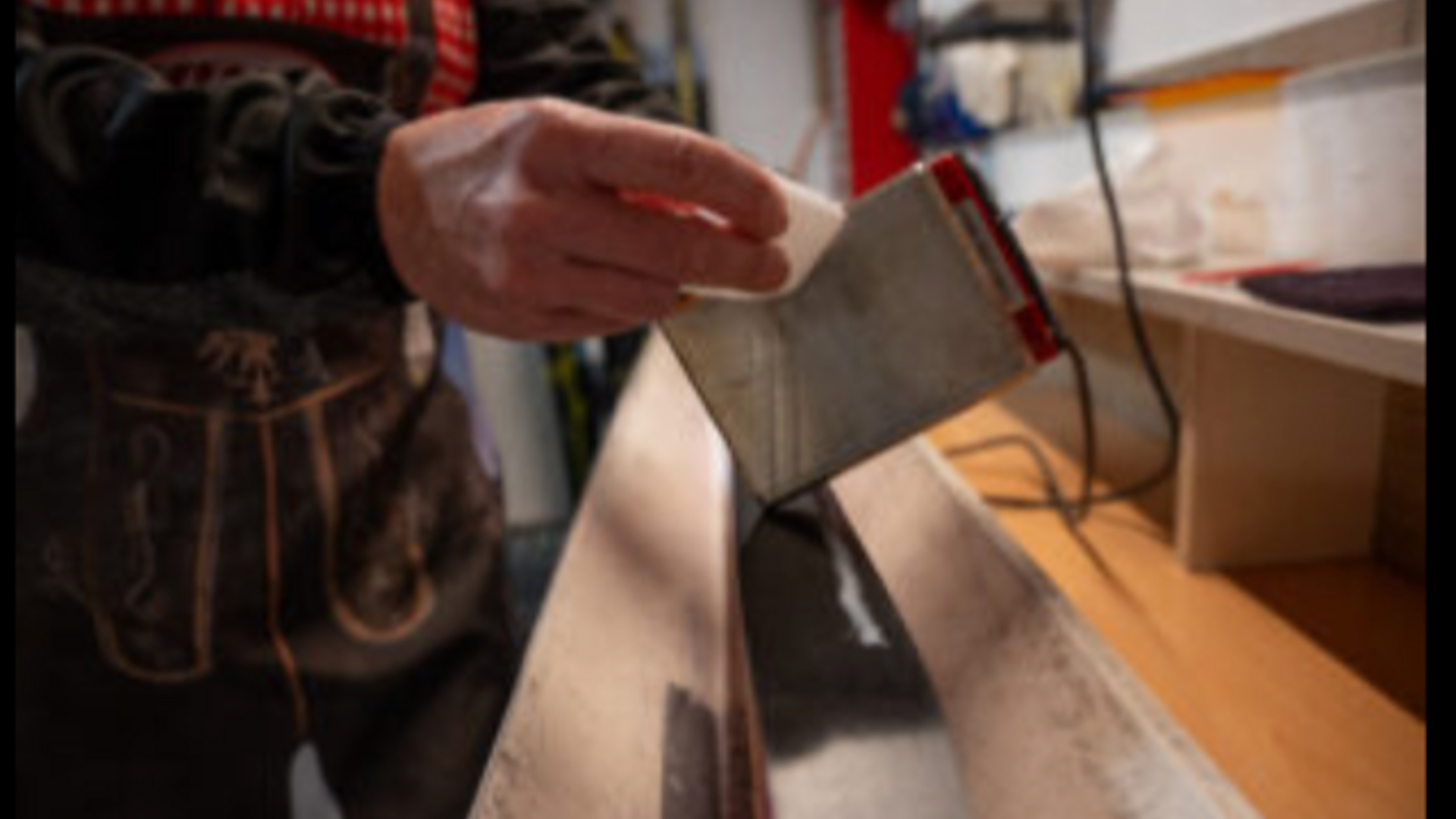 Hand schmiert Ski mit Wachs auf Werkbank