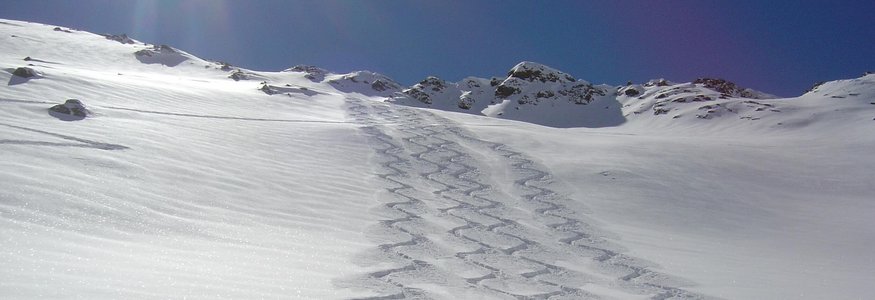 Zwei Spuren von Skifahrern im unberührten Pulverschnee auf einer Bergpiste