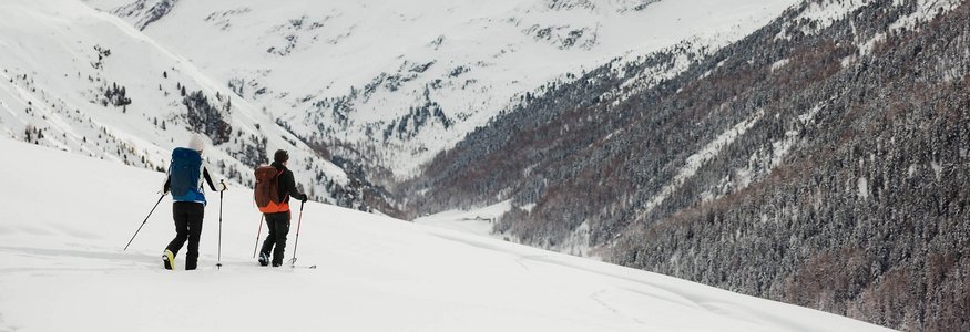 Zwei Menschen wandern mit Schneeschuhen in verschneiten Bergen
