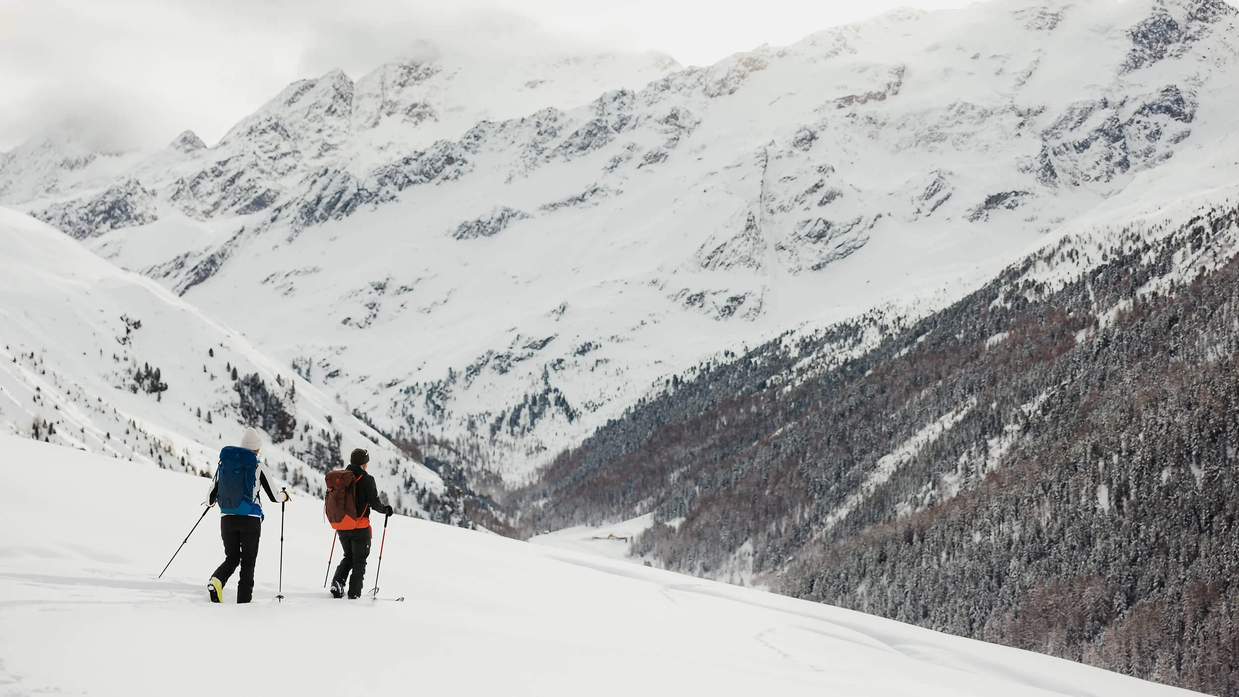 Zwei Menschen wandern mit Schneeschuhen in verschneiten Bergen