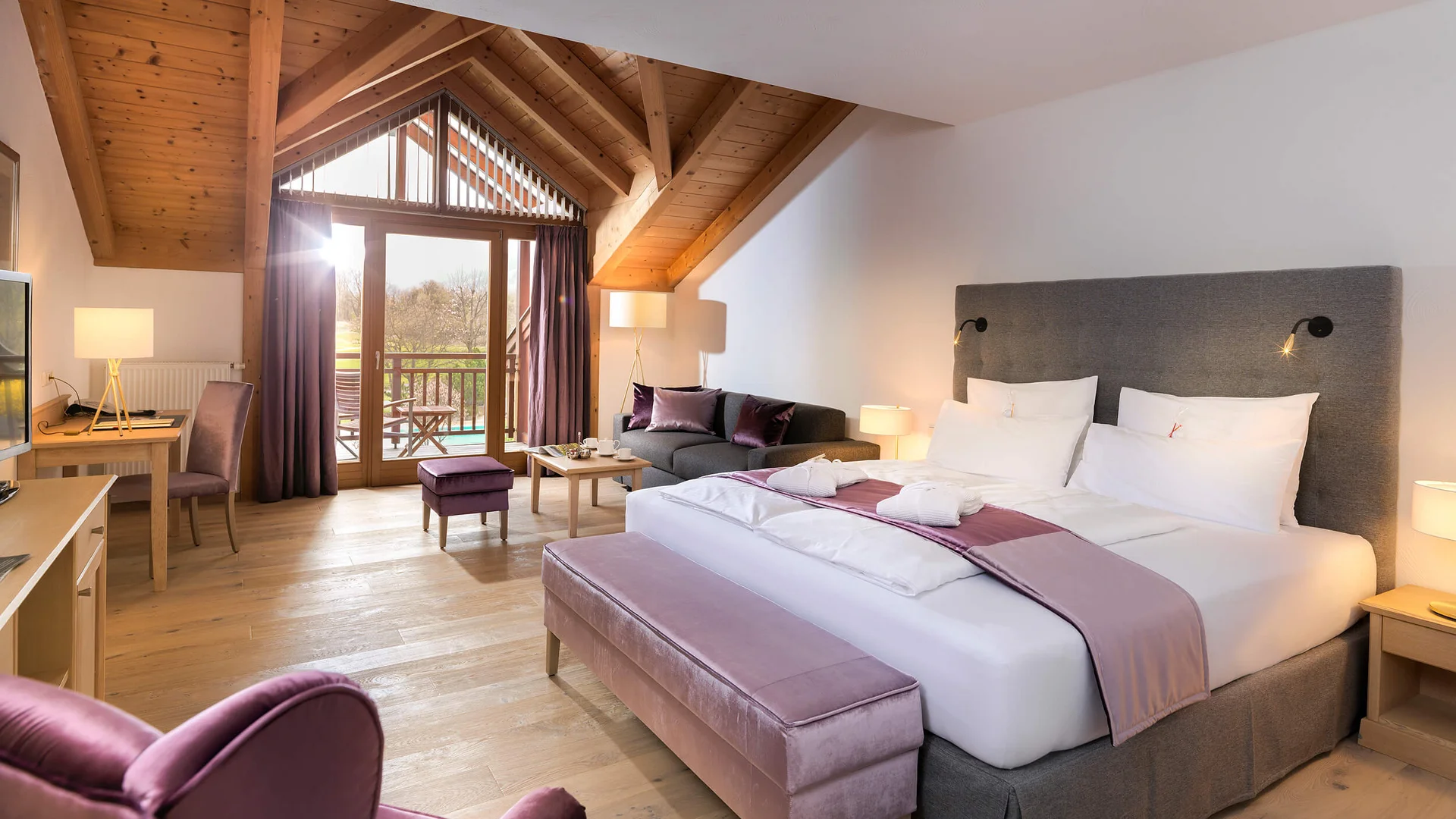 Helles Hotelzimmer mit Doppelbett, Sitzecke und Holzbalkendecke