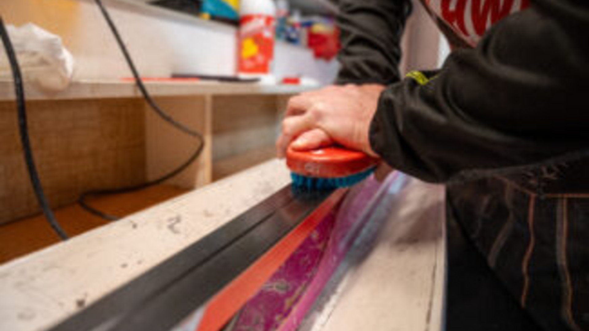 Person reinigt Oberfläche einer Skibindung mit Bürste