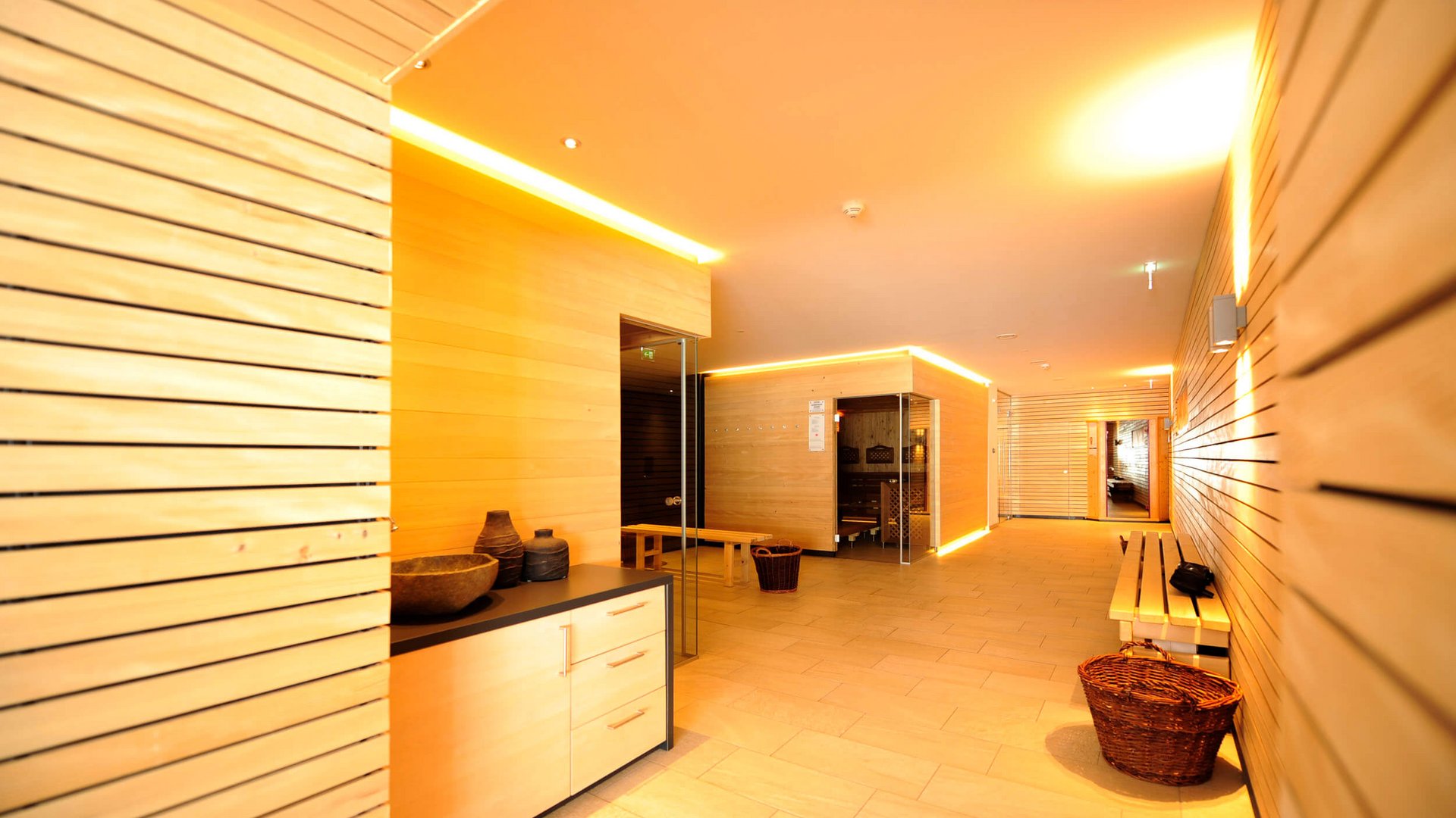 Brightly lit sauna area with wooden bench and basket