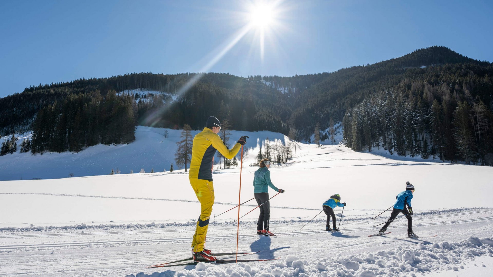 Familie beim Langlaufen auf verschneiter Berglandschaft bei Sonnenschein