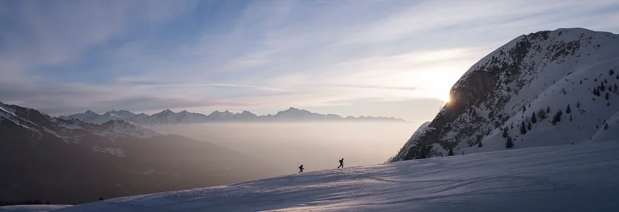 Ratschings © Ratschings Tourismus - Manuel Kottersteger Zwei Skifahrer auf verschneitem Berg bei Sonnenuntergang