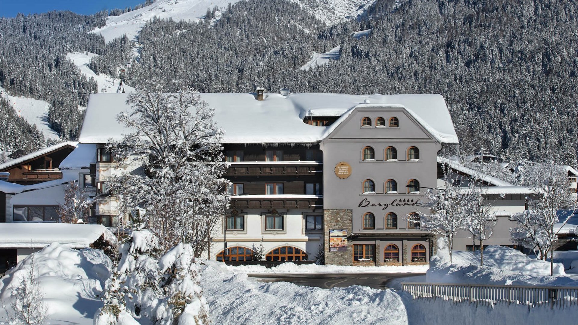Hotel Bergland covered in snow with snowy mountains in the background