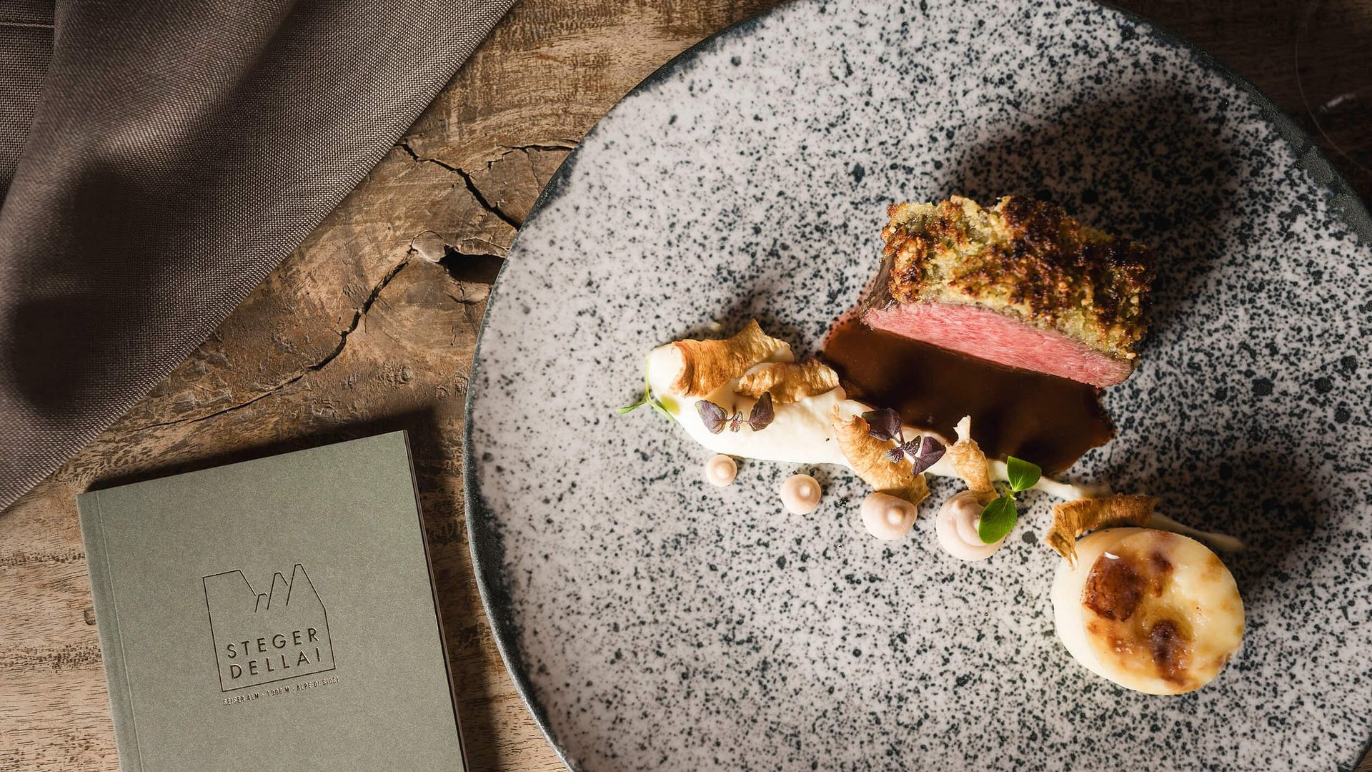 Gourmetgericht mit Rinderfilet und Beilagen auf speckigem Teller