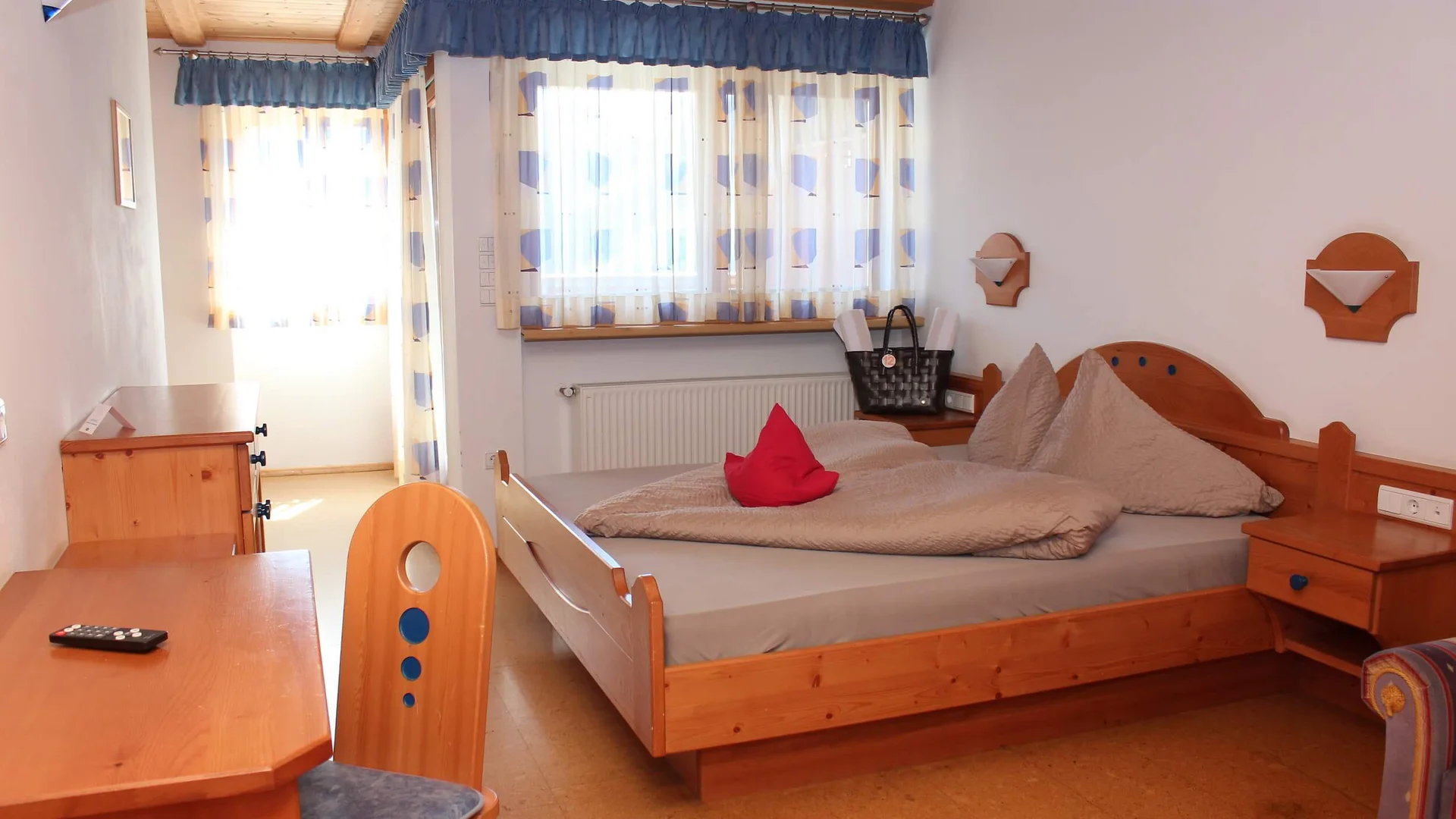Gemütliches Schlafzimmer mit Holzmöbeln und bunten Vorhängen