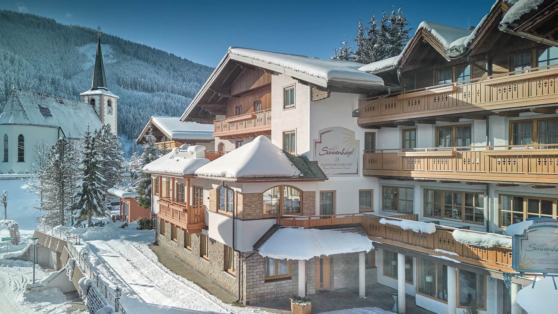 Snow-covered mountain lodge beside a church in winter
