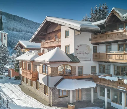 Snow-covered mountain lodge beside a church in winter