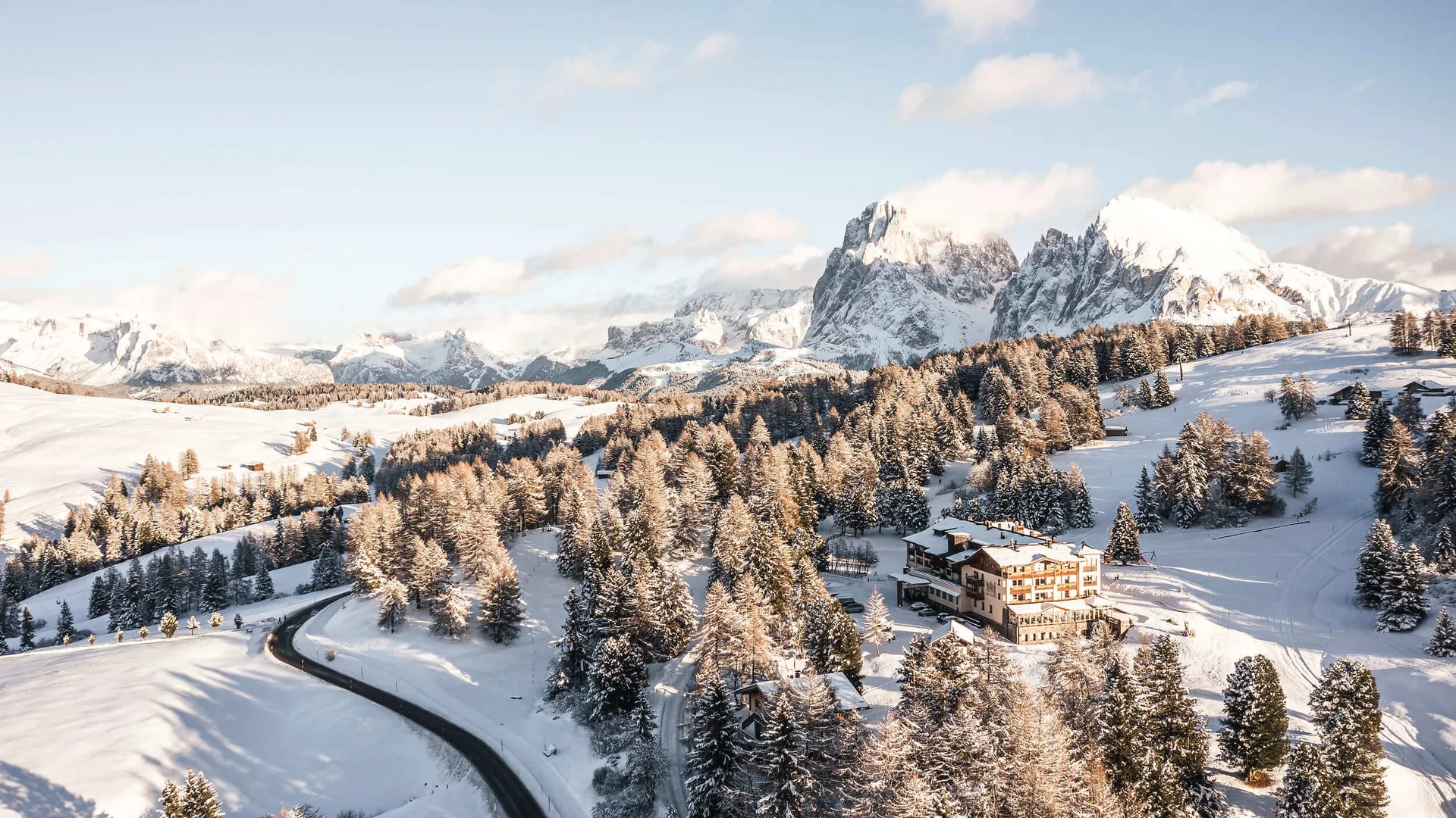 Verschneite Landschaft mit Bergen, Bäumen und einem Hotel im Winter