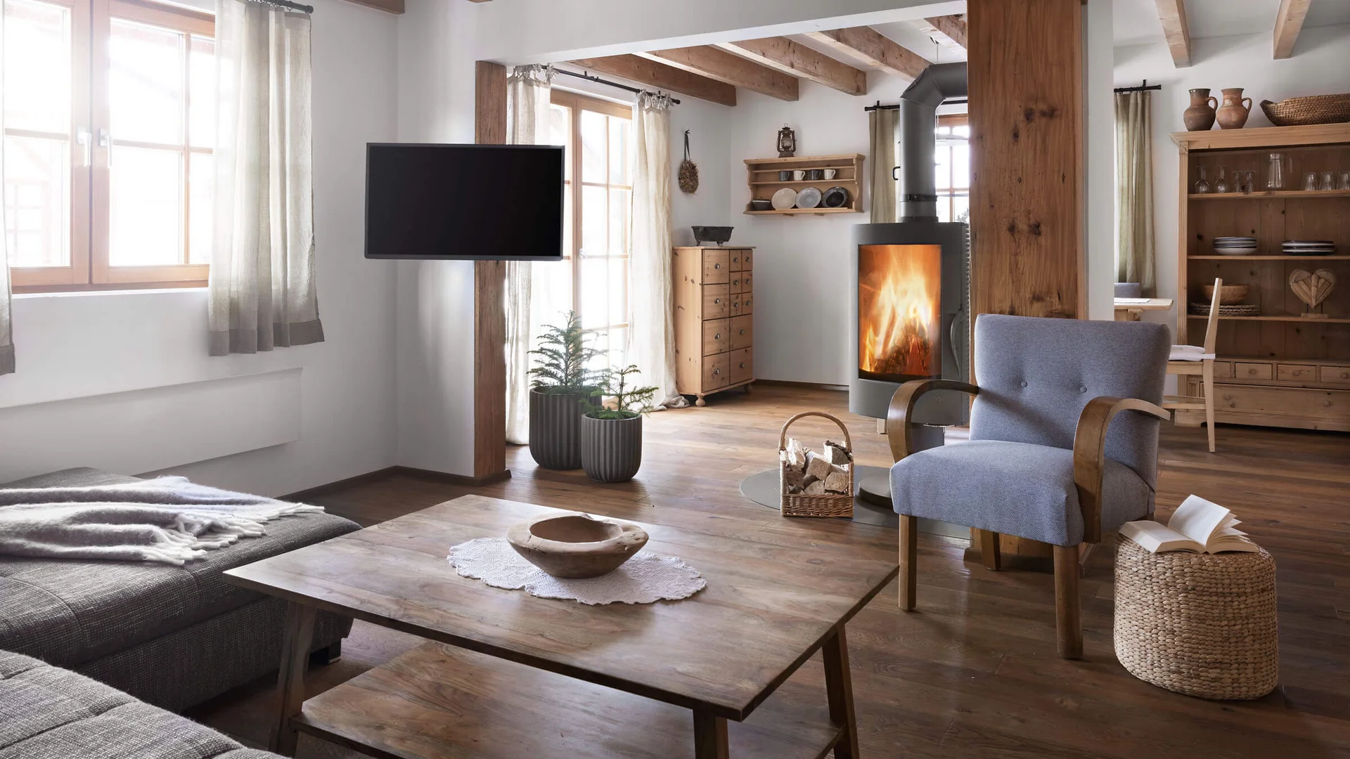 SLOHO Bergurlaub Apartments © Cathrine Stukhard Helles Wohnzimmer mit Kamin, Sessel, Sofa, Holzbalken und Couchtisch