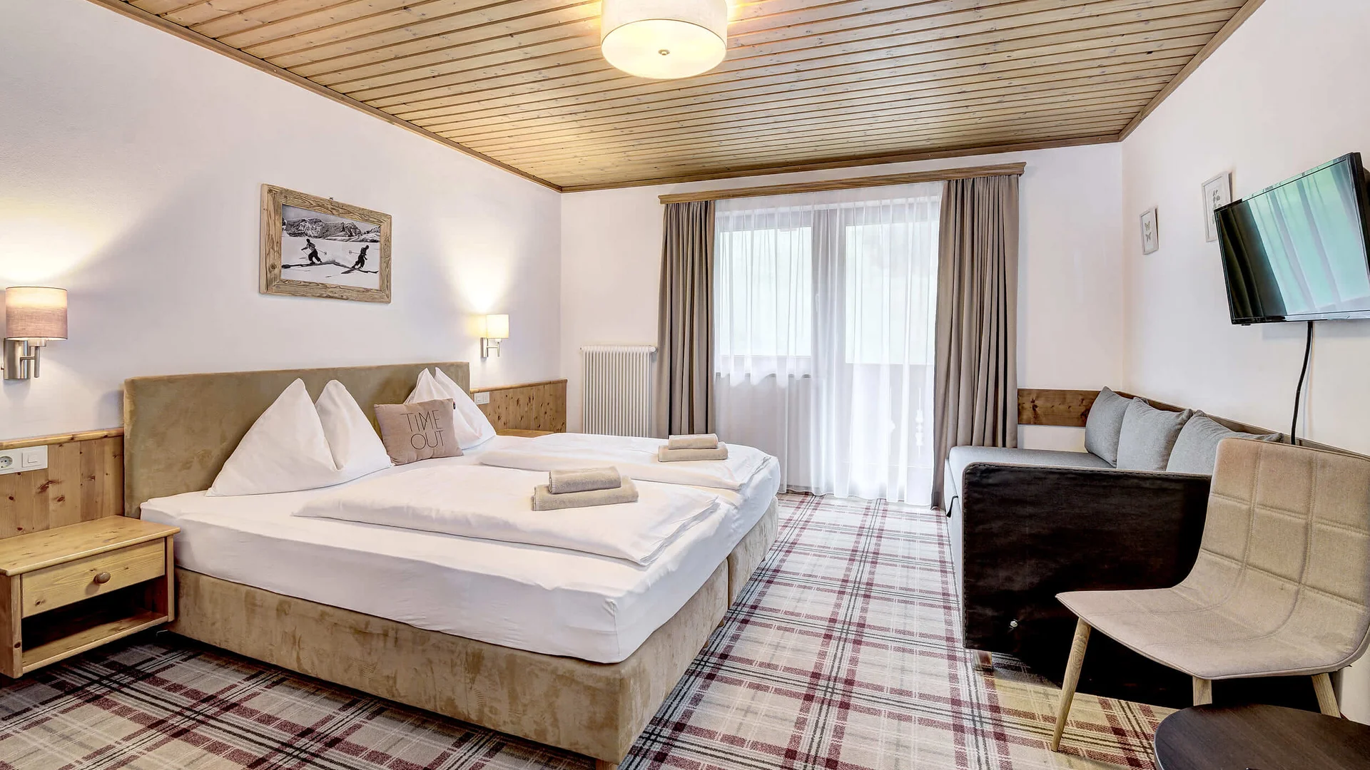 Cozy hotel room with double bed, sofa, and TV