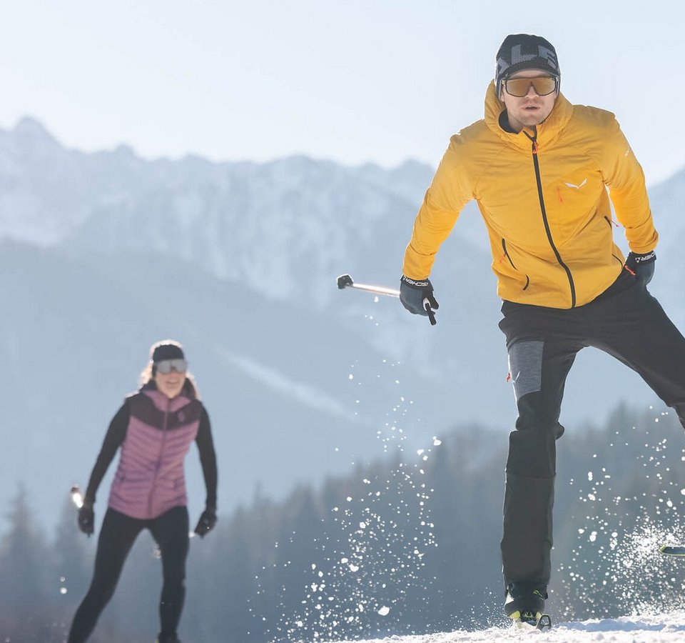 Langlaufurlaub im Das Walchsee
© Mathäus Gartner Zwei Langläufer auf schneebedecktem Feld vor Bergkulisse bei Sonnenschein