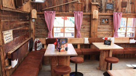 Gemütliche Holzhütte mit Tisch und Sitzbänken im alpinen Stil
