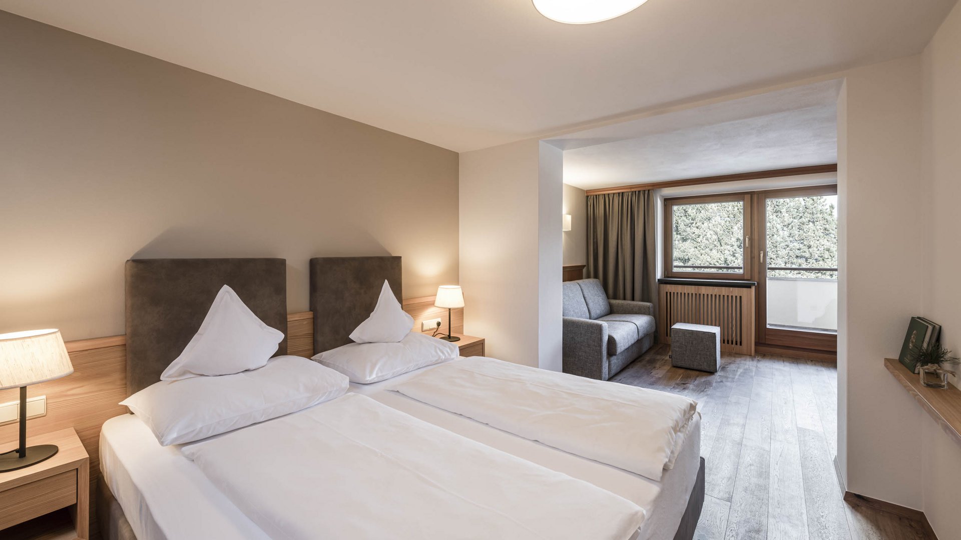 Modern eingerichtetes Hotelzimmer mit zwei Betten und Sitzecke am Fenster