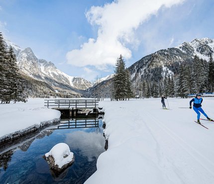 Langläufer unterwegs auf verschneiter Winterlandschaft mit Bergen und Wald