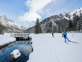 Cross-country skiers on snowy winter trail in mountain landscape with forest