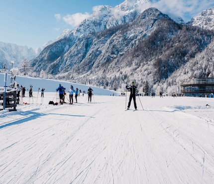 Langläufer auf verschneiter Piste mit Bergen im Hintergrund