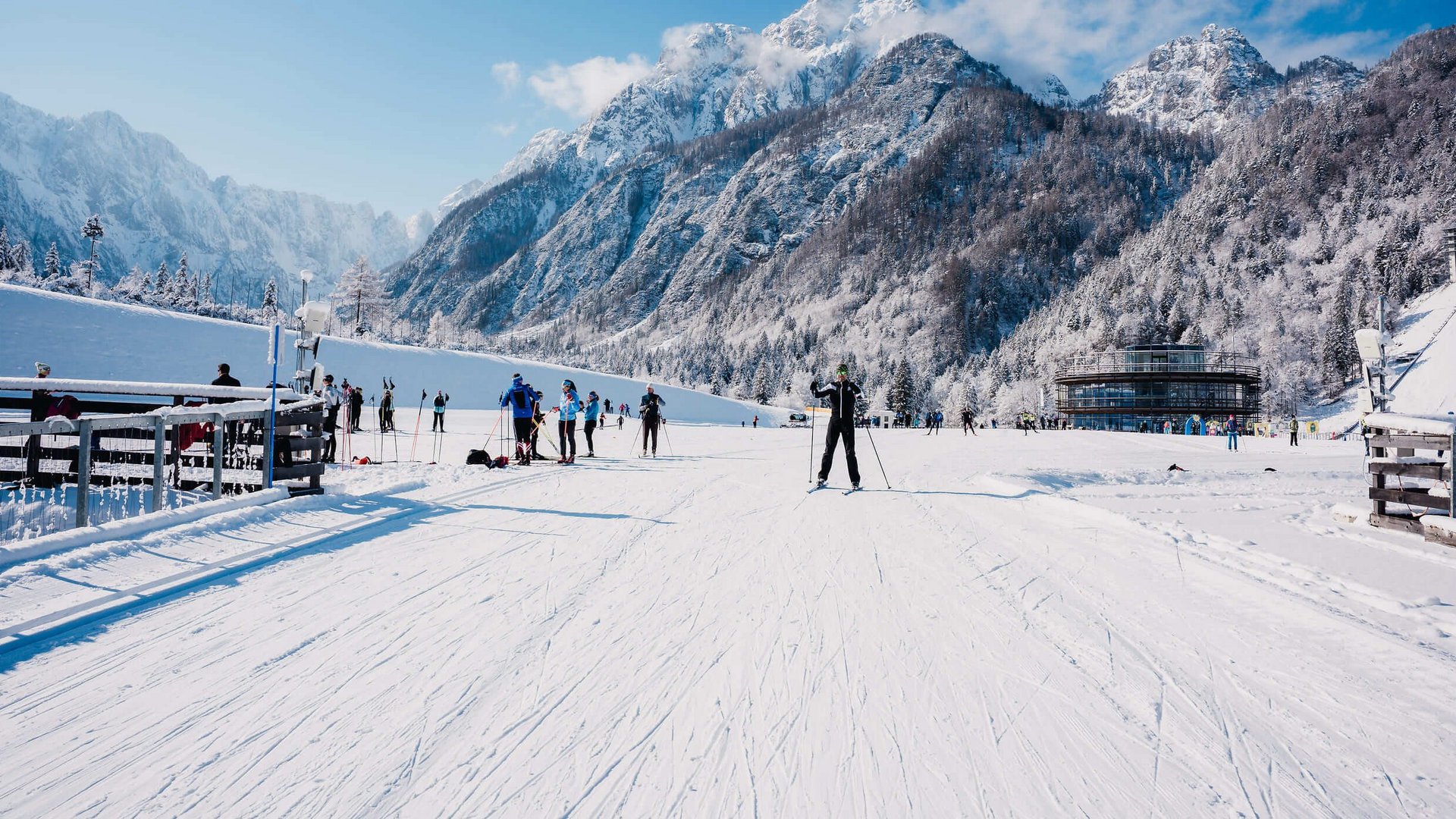 Cross-country skiers on snowy trail with mountains in background