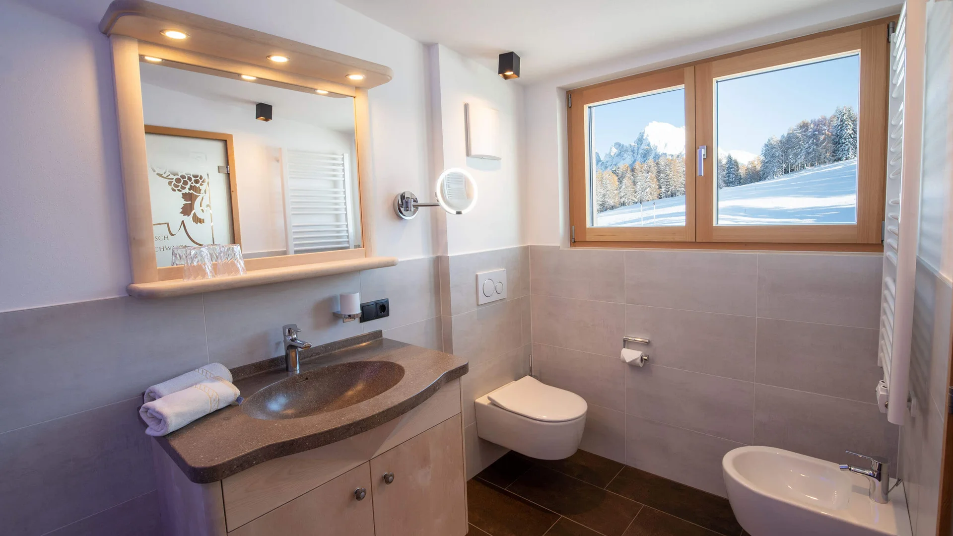 Modern bathroom with window showing snowy mountains and trees