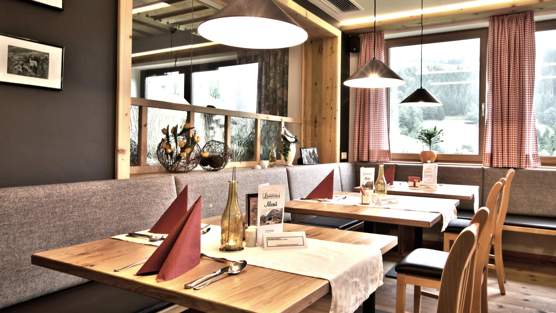 Gemütlicher Restaurantinnenraum mit Holztischen und roten Servietten