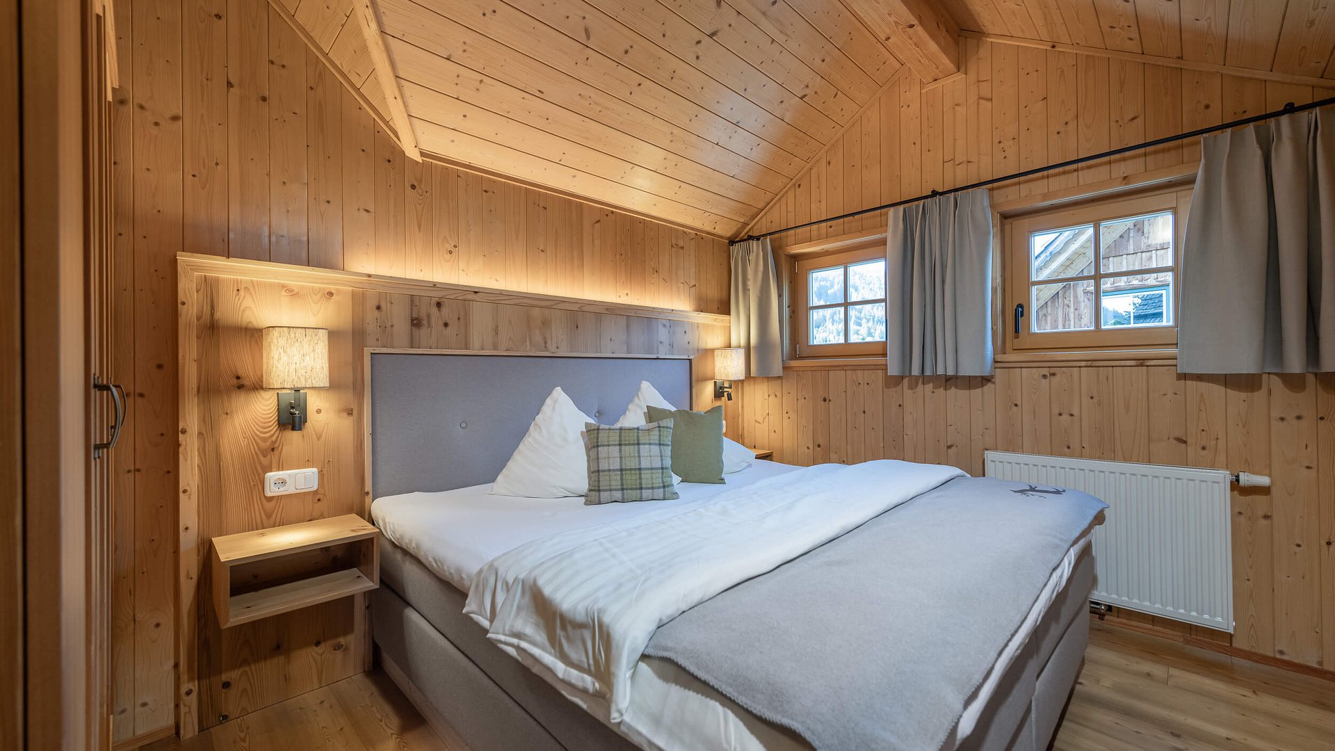 Cozy bedroom with wooden walls, double bed and windows with curtains