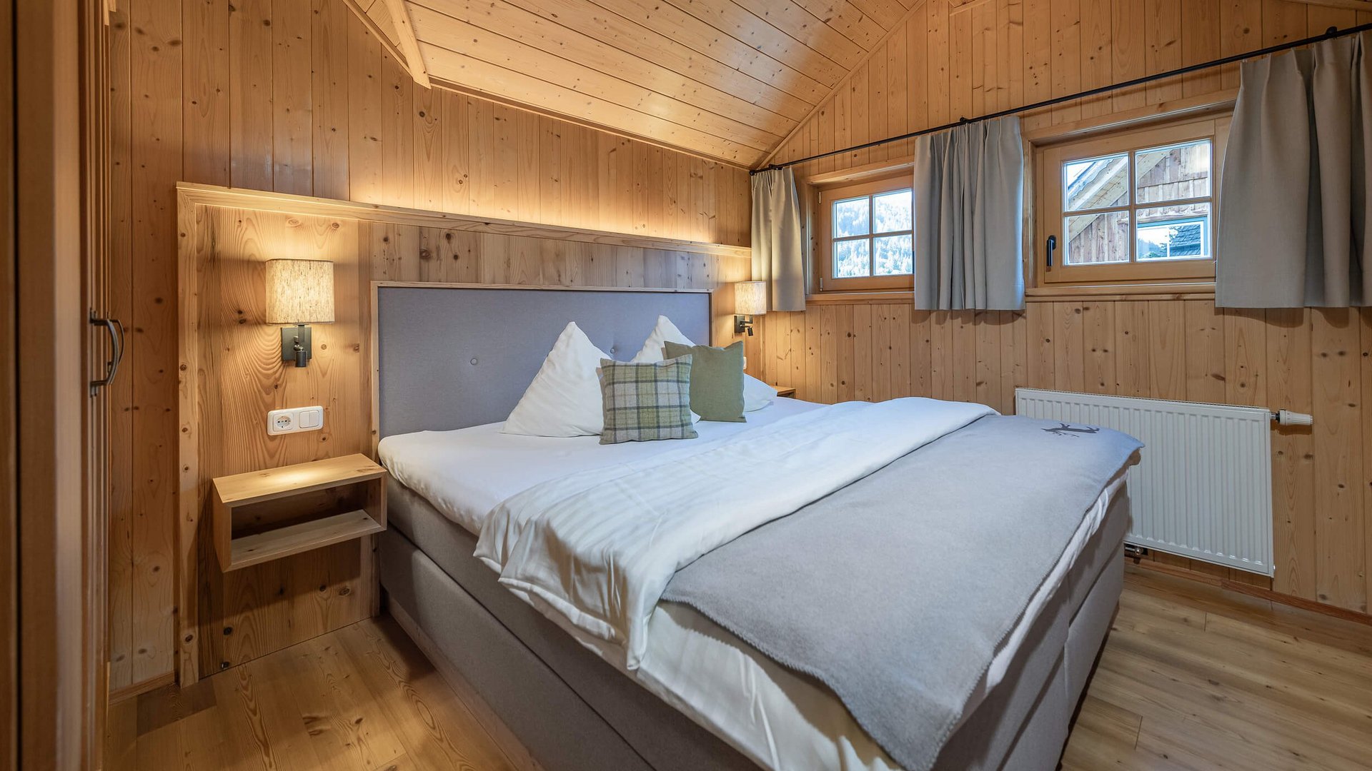 Cozy bedroom with wooden walls, double bed and windows with curtains
