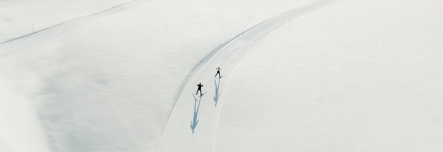 Zwei Langläufer auf verschneiter Loipe in den Bergen