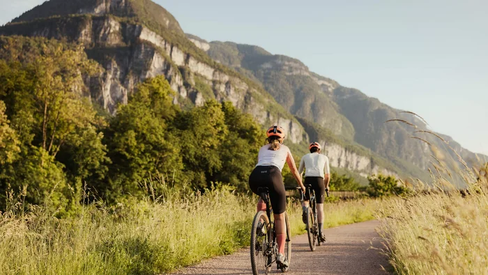 Zwei Radfahrer fahren auf einem Weg mit Bergen im Hintergrund