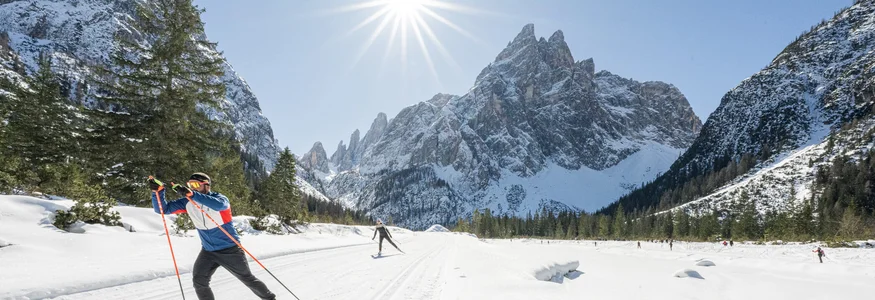 Langläufer im verschneiten Gebirgstal bei strahlendem Sonnenschein