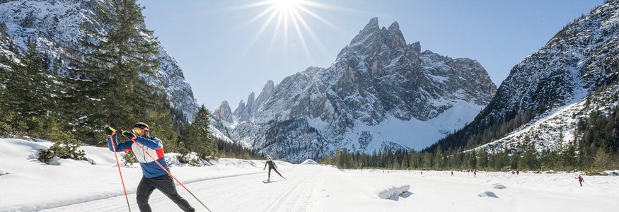 Langläufer im verschneiten Gebirgstal bei strahlendem Sonnenschein