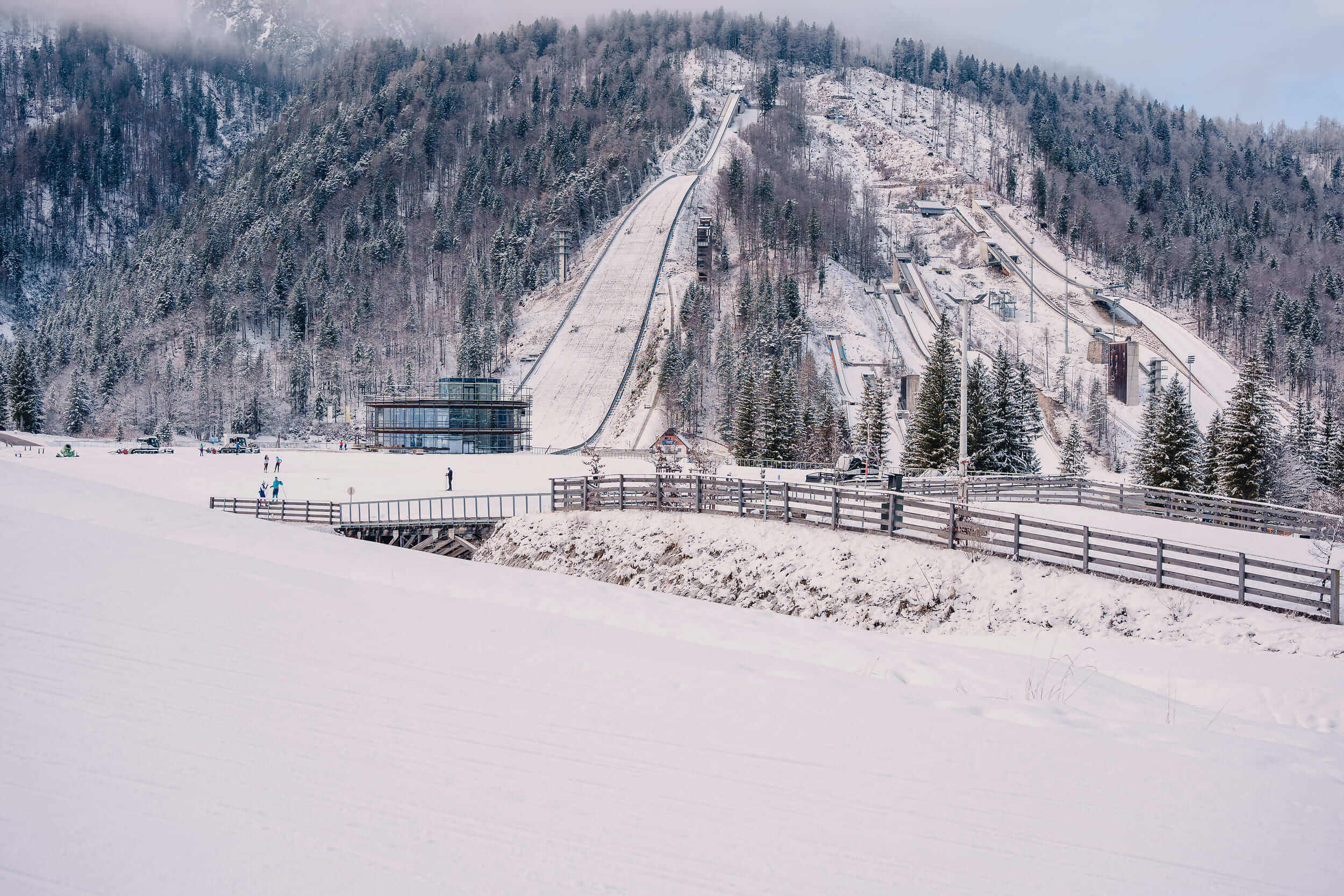 Snow-covered ski jumps in winter with trees and fog